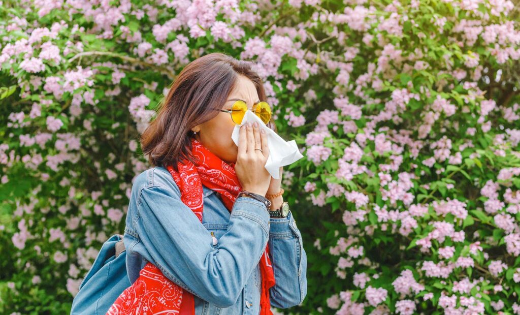 Woman blowing her nose due to seasonal allergies