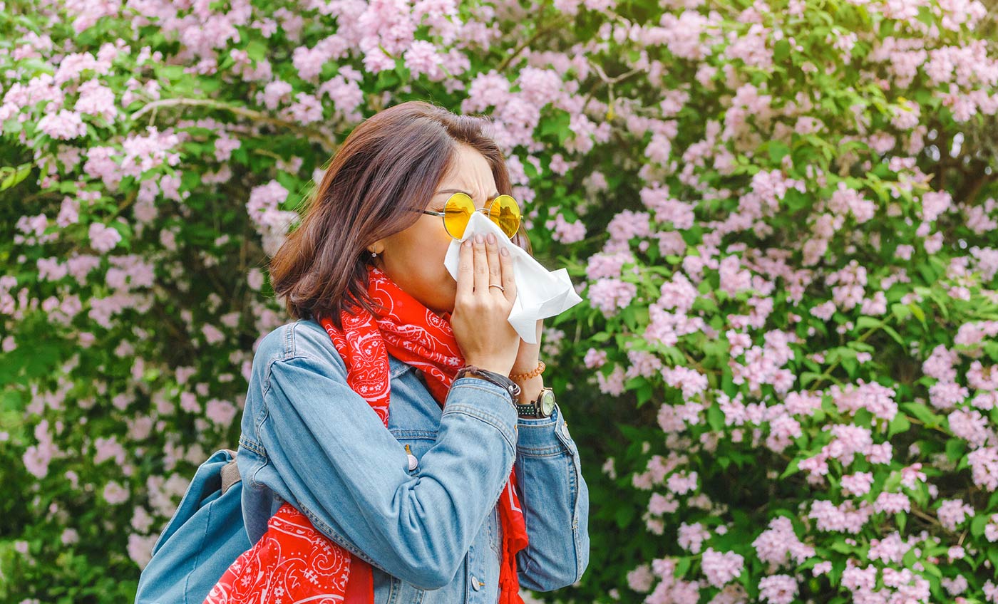 Woman blowing her nose due to seasonal allergies