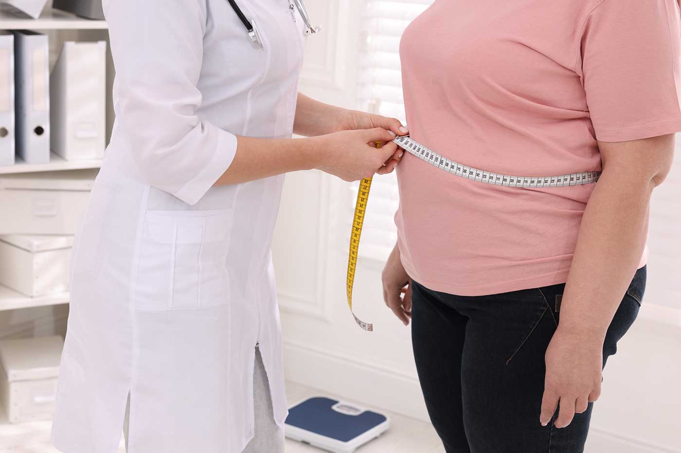 Nurse measuring a woman's waist to track weight loss