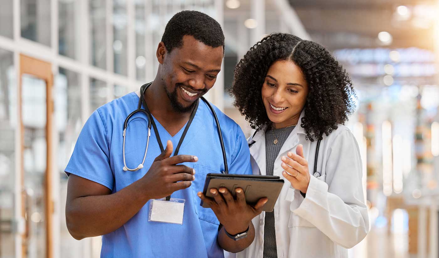 Two happy doctors looking at ther schedule on a tablet