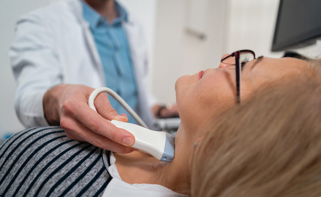 Doctor administering ultrasound to patient neck